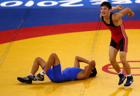 SINGAPORE - AUGUST 15:  Urmatbek Amatov of Kyrgyzstan celebrates his win against Olexander Lytvynov of the Ukraine in the final of the Men's Greco Roman 58kg Wrestling competition on day one of the Youth Olympics at the International Convention Centre on August 15, 2010 in Singapore.  <br /><br /><span class="help">(Photo by Mark Dadswell/Getty Images)</span>