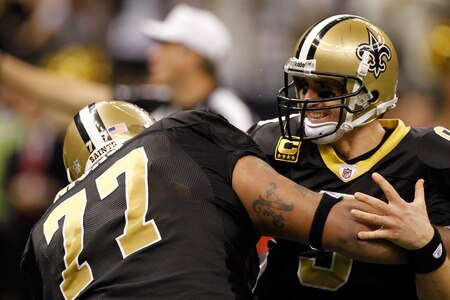NEW ORLEANS, LA - DECEMBER 26:  Quarterback Drew Brees #9 of the New Orleans Saints is picked up by offensive guard Carl Nicks #77 after Brees throws a nine-yard touchdown pass to running back Darren Sproles #43 and breaks the single-season passing record in the fourth quarter against the Atlanta Falcons at the Mercedes-Benz Superdome on December 26, 2011 in New Orleans, Louisiana.  <br /><br /><span class="help">(Photo by Chris Graythen/Getty Images)</span>