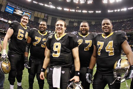 NEW ORLEANS, LA - DECEMBER 26:  Quarterback Drew Brees #9 of the New Orleans Saints celebrates with his offensive line after throwing a nine-yard touchdown pass break the single-season passing record in the fourth quarter against the Atlanta Falcons at the Mercedes-Benz Superdome on December 26, 2011 in New Orleans, Louisiana.  <br /><br /><span class="help">(Photo by Chris Graythen/Getty Images)</span>