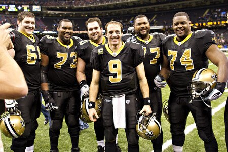 NEW ORLEANS, LA - DECEMBER 26:   Quarterback Drew Brees #9 and the offensive line of the New Orleans Saints pose after the game for a photo after Brees threw a nine-yard touchdown pass to running back Darren Sproles #43 and broke the single-season passing record in the fourth quarter against the Atlanta Falcons at Mercedes-Benz Superdome on December 26, 2011 in New Orleans, Louisiana.  The Saints defeated the Falcons 45-16.  <br /><br /><span class="help">(Photo by Wesley Hitt/Getty Images)</span>