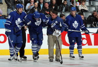 TORONTO - MARCH 7:  John Mitchell #39 and head athletic therapist Rudy Cantu of the Toronto Maple Leafs help Mike Van Ryn #26 off the ice as Jason Blake #55 looks on during the game against the Edmonton Oilers at Air Canada Centre on March 7, 2009 in Toronto, Ontario, Canada. (Photo by Dave Sandford/Getty Images)