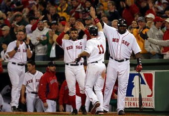 BOSTON - OCTOBER 16:  Mark Kotsay #11 of the Boston Red Sox is greeted by teammates David Ortiz #34 and Jason Varitek #33 after scoring the tying run in the eighth inning against the Tampa Bay Rays in game five of the American League Championship Series during the 2008 MLB playoffs at Fenway Park on October 16, 2008 in Boston, Massachusetts.  (Photo by Elsa/Getty Images)