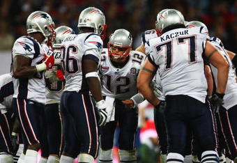 LONDON, ENGLAND - OCTOBER 25:  Tom Brady (#12) of the New England Patriots discusses tactics with his team mates during the NFL International Series match between New England Patriots and Tampa Bay Buccaneers at Wembley Stadium on October 25, 2009 in London, England. This is the third occasion where a regular season NFL match has been played in London.  (Photo by Julian Finney/Getty Images)