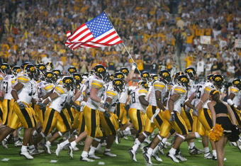 MIAMI - JANUARY 2:  The Iowa Hawkeyes take the field against USC as a team member holds the United States flag before the FedEx Orange Bowl on January 2, 2003 at Pro Player Stadium in Miami, Florida.  USC defeated Iowa 38-17.  (Photo by Eliot J. Schechter/Getty Images)