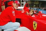 TOKYO - OCTOBER 8:  Michael Schumacher of Germany and Ferrari poses with a local child during an appearance at the Showa Shell headquarters on October 8, 2003 in Tokyo, Japan. (Photo by Clive Mason/Getty Images).