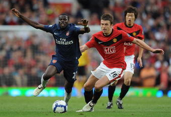 MANCHESTER, UNITED KINGDOM - AUGUST 29:   Emmanuel Eboue of Arsenal is challenged by Michael Carrick of Manchester United during the Barclays Premier League match between Manchester United and Arsenal at Old Trafford on August 29, 2009 in Manchester, England. (Photo by Laurence Griffiths/Getty Images)