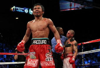LAS VEGAS - NOVEMBER 14:  Manny Pacquiao celebrates his 12 round TKO victory against Miguel Cotto as Cotto is consoled by referee Kenny Bayless after their WBO welterweight title fight at the MGM Grand Garden Arena on November 14, 2009 in Las Vegas, Nevada.  (Photo by Al Bello/Getty Images)
