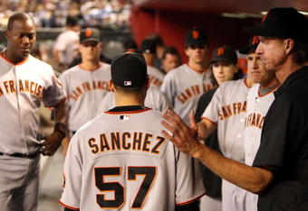 PHOENIX - JUNE 11:  Starting pitcher Jonathan Sanchez #57 of the San Francisco Giants is greeted by Randy Johnson (R) and teammates after being removed from the major league baseball game against the Arizona Diamondbacks at Chase Field on June 11, 2009 in Phoenix, Arizona.  The Diamondbacks defeated the Giants 2-1. (Photo by Christian Petersen/Getty Images)