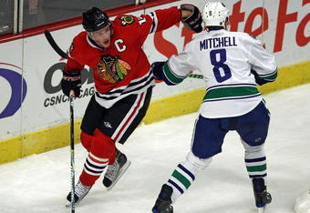 CHICAGO - OCTOBER 21: Jonathan Toews #19 of the Chicago Blackhawks controls for the puck against Willie Mitchell #8 of the Vancouver Canucks at the United Center on October 14, 2009 in Chicago, Illinois. The Canucks defeated the Blackhawks 3-2. (Photo by Jonathan Daniel/Getty Images)
