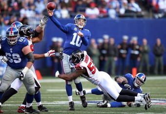EAST RUTHERFORD, NJ - NOVEMBER 22:  Eli Manning #10 of the New York Giants completes a pass under pressure from John Abraham #55 of the Atlanta Falcons on November 22, 2009 at Giants Stadium in East Rutherford, New Jersey.  (Photo by Jim McIsaac/Getty Images)