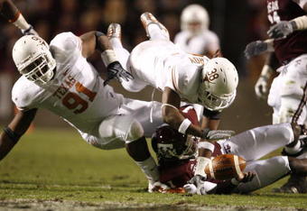 COLLEGE STATION, TX - NOVEMBER 26: Quarterback Jerrod Johnson #1 of the Texas A&M Aggies loses control of the ball as defensive tackle Kheeston Randall #91 and linebacker Roddrick Muckelroy #38 of the Texas Longhorns go for the loose ball in the first half at Kyle Field on November 26, 2009 in College Station, Texas. The officials ruled that Johnson was down before losing control of the ball. (Photo by Aaron M. Sprecher/Getty Images)