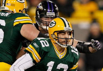 GREEN BAY, WI - DECEMBER 07: Aaron Rodgers #12 of the Green Bay Packers ducks as Paul Kruger #99 of the Baltimore Ravens rushes against Chad Clifton #76 at Lambeau Field on December 7, 2009 in Green Bay, Wisconsin. The Packers defeated the Ravens 27-17. (Photo by Jonathan Daniel/Getty Images)