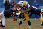 CHICAGO - DECEMBER 13: Ryan Grant #25 of the Green Bay Packers tries to break away from Lance Briggs #55 and Gaines Adams #99 of the Chicago Bears at Soldier Field on December 13, 2009 in Chicago, Illinois. The Packers defeated the Bears 21-14. (Photo by Jonathan Daniel/Getty Images)