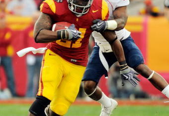 LOS ANGELES, CA - DECEMBER 05:  Tailback Allen Bradford #21 of the USC Trojans drags cornerback Devin Ross #6 of the Arizona Wildcats as he rushes for a gain during the second quarter of the NCAA college football game at the Los Angeles Coliseum on December 5, 2009 in Los Angeles, California.  (Photo by Kevork Djansezian/Getty Images)
