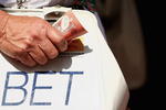 MELBOURNE, AUSTRALIA - OCTOBER 31:  A bookie holds onto his money during the 2009 Victoria Derby Day meeting at Flemington Racecourse on October 31, 2009 in Melbourne, Australia.  (Photo by Quinn Rooney/Getty Images)