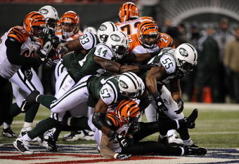 EAST RUTHERFORD, NJ - JANUARY 03:  Bart Scott #57 of the New York Jets takes down Larry Johnson #27 of the Cincinnati Bengals with the help of the defensive line during the second half of the game at Giants Stadium on January 3, 2010 in East Rutherford, New Jersey. The Jets defeated the Bengals 37-0.  (Photo by Jeff Zelevansky/Getty Images)