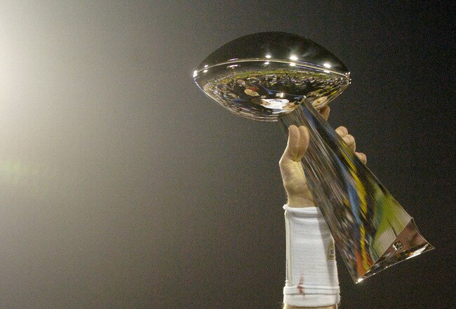Tom Brady holds the Vince Lombardi Trophy as he stands on the podium after The New England Patriots defeated The Philadelphia Eagles in Super Bowl XXXIX at Alltel Staduim in Jacksonville, Florida.  (Photo by Al Messerschmidt/Getty Images)
