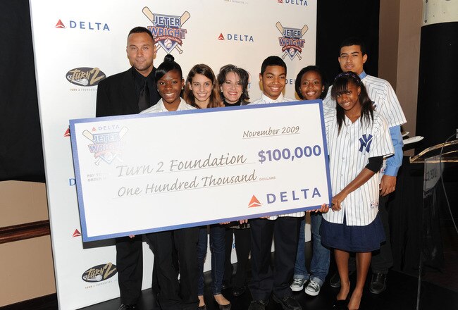 NEW YORK - NOVEMBER 13:  New York Yankees baseball player Derek Jeter, Gail Grimmett, Senior Vice president of New York Delta (4th from left) and children from the Turn 2 Foundation attend Delta's donation to the Derek Jeter Turn 2 Foundation at ESPN Zone in Times Square on November 13, 2009 in New York City.  (Photo by Jason Kempin/Getty Images)
