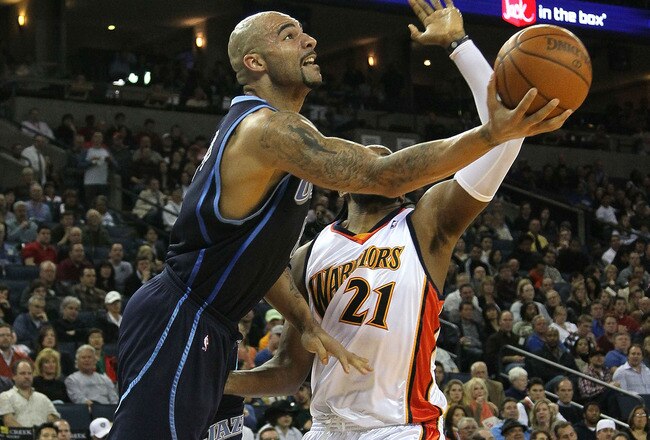 OAKLAND, CA - FEBRUARY 19:  Carlos Boozer #5 of the Utah Jazz shoots against Ronny Turiaf #21 of the Golden State Warriors during an NBA game at Oracle Arena at Oracle Arena on February 19, 2010 in Oakland, California.  NOTE TO USER: User expressly acknowledges and agrees that, by downloading and/or using this Photograph, user is consenting to the terms and conditions of the Getty Images License Agreement.  (Photo by Jed Jacobsohn/Getty Images)