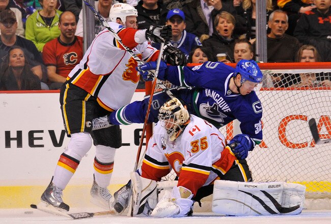 VANCOUVER, CANADA - MARCH 14: Jannik Hansen #36 of the Vancouver Canucks crashes into goalie Vesa Toskala #35 of the Calgary Flames after getting hit by Flames Jay Bouwmeester #4 during the third period of NHL action on March 14, 2010 at General Motors Place in Vancouver, British Columbia, Canada.  (Photo by Rich Lam/Getty Images)