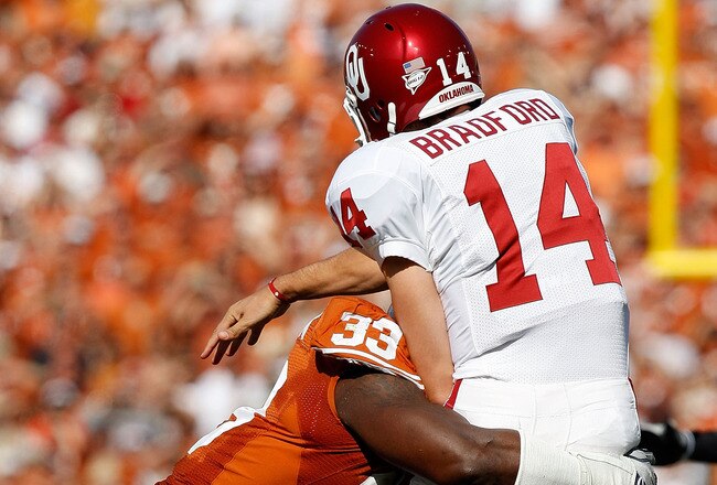 DALLAS - OCTOBER 17:  Quarterback Sam Bradford #14 of the Oklahoma Sooners is tackled by Lamarr Houston #33 of the Texas Longhorns at Cotton Bowl on October 17, 2009 in Dallas, Texas.  (Photo by Ronald Martinez/Getty Images)