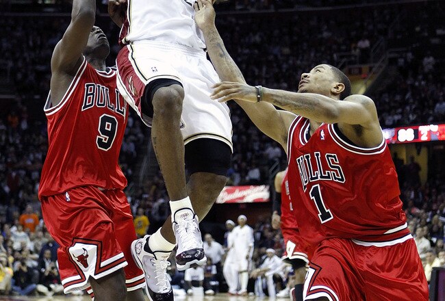 CLEVELAND - APRIL 17:  LeBron James #23 of the Cleveland Cavaliers gets to the basket between Derrick Rose #1 and Luol Deng #9 of the Chicago Bulls in Game One of the Eastern Conference Quarterfinals during the 2010 NBA Playoffs at Quicken Loans Arena on April 17, 2010 in Cleveland, Ohio. Cleveland won the game 96-83 to take a 1-0 series lead. NOTE TO USER: User expressly acknowledges and agrees that, by downloading and or using this photograph, User is consenting to the terms and conditions of the Getty Images License Agreement.  (Photo by Gregory Shamus/Getty Images)