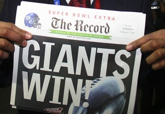 GLENDALE, AZ - FEBRUARY 03:  Defensive end Michael Strahan #92 of the New York Giants holds a copy of the Bergen Record with the headline 'GIANTS WIN!' after the Giants defeated the New England Patriots 17-14 during Super Bowl XLII on February 3, 2008 at the University of Phoenix Stadium in Glendale, Arizona.  (Photo by Donald Miralle/Getty Images)