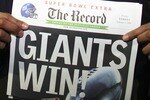 GLENDALE, AZ - FEBRUARY 03:  Defensive end Michael Strahan #92 of the New York Giants holds a copy of the Bergen Record with the headline 'GIANTS WIN!' after the Giants defeated the New England Patriots 17-14 during Super Bowl XLII on February 3, 2008 at the University of Phoenix Stadium in Glendale, Arizona.  (Photo by Donald Miralle/Getty Images)