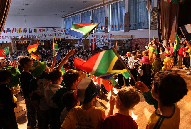 JOHANNESBURG, SOUTH AFRICA - JUNE 08:  Primary school children wave the South African flag while performing in a play to celebrate the soccer World Cup on June 8, 2010 in Johannesburg, South Africa. Jewish children from the King David Victory Park Primary School completed their final dress rehersal before performing in two sold out shows highlighting South African enthusiasm for the World Cup, which begins Friday.  (Photo by John Moore/Getty Images)