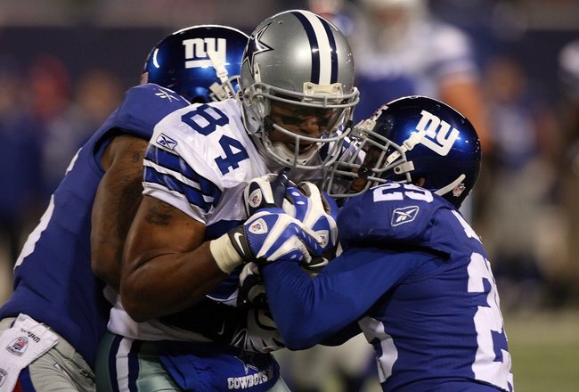 EAST RUTHERFORD, NJ - DECEMBER 06: Aaron Rouse #26 and Bruce Johnson #25 (R) of the New York Giants attempt to strip Patrick Crayton #84 of the Dallas Cowboys after Crayton made a reception in the fourth quarter at Giants Stadium on December 6, 2009 in East Rutherford, New Jersey. (Photo by Jim McIsaac/Getty Images)