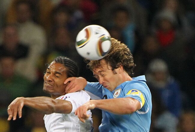 CAPE TOWN, SOUTH AFRICA - JUNE 11: Florent Malouda of France goes up for a challenge with Diego Lugano of Uruguay during the 2010 FIFA World Cup South Africa Group A match between Uruguay and France at Green Point Stadium on June 11, 2010 in Cape Town, South Africa.  (Photo by Doug Pensinger/Getty Images)