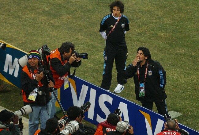 JOHANNESBURG, SOUTH AFRICA - JUNE 27:  Diego Maradona head coach of Argentina acknowledges the support as his players warm up prior to the 2010 FIFA World Cup South Africa Round of Sixteen match between Argentina and Mexico at Soccer City Stadium on June 27, 2010 in Johannesburg, South Africa.  (Photo by Lars Baron/Getty Images)