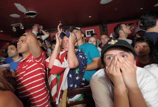 NEW YORK - JUNE 26:   (L-R) Amey Raje, Matt Silver and Roxana Grozo watch a televised 2010 FIFA World Cup South Africa match between USA and Ghana at Jack Demsey's bar on June 26, 2010 in New York City. The United States team was defeated 2-1 by Ghana in overtime, eliminating them from the tournament.  (Photo by Michael Loccisano/Getty Images)