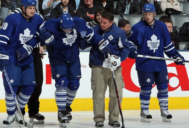 TORONTO - MARCH 7:  John Mitchell #39 and head athletic therapist Rudy Cantu of the Toronto Maple Leafs help Mike Van Ryn #26 off the ice as Jason Blake #55 looks on during the game against the Edmonton Oilers at Air Canada Centre on March 7, 2009 in Toronto, Ontario, Canada. (Photo by Dave Sandford/Getty Images)