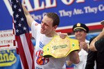 NEW YORK - JULY 4:   Joey Chestnut (L) of San Jose, California holds up the American flag and his champion belt after defeating Takeru Kobayashi of Nagano, Japan and Patrick 'deep dish' Bertoletti in the Nathan's Famous Fourth of July hot dog eating contest on July 4, 2009 in Coney Island in the Brooklyn borough of New York City. Chestnut defeated Kobayashi with eating 68 to his 64.5 hotdogs. Kobayashi won six previous competitions before tying last year with Chestnut.  (Photo by Yana Paskova/Getty Images)