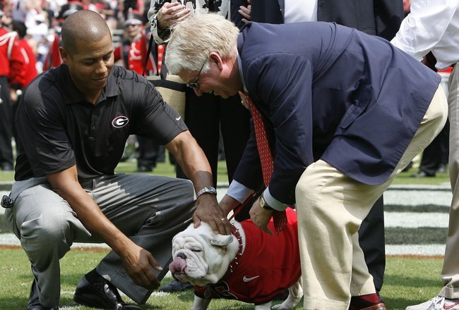 ATHENS - AUGUST 30:  University of Georgia athletic director Damon Evans (L) and school president Michael Adams put a new collar on UGA VII before the game against the Georgia Southern Eagles at Sanford Stadium on August 30, 2008 in Athens, Georgia.  This game is UGA VII's first game as the official school mascot.  (Photo by Mike Zarrilli/Getty Images)