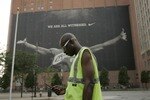 CLEVELAND - JULY 8:  A parking attendant stands near a larger than life photograph of LeBron James July 8, 2010 in Cleveland, Ohio. The two-time Most Valuable Player has the choice of remaining with the Cleveland Cavaliers or signing with a new team. (Photo by J.D. Pooley/Getty Images)