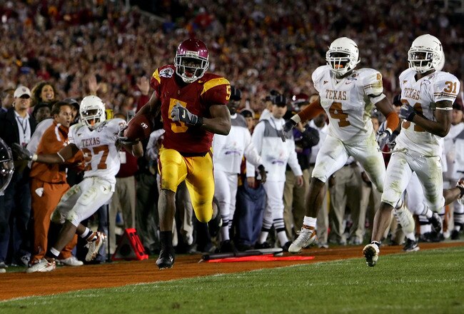 PASADENA, CA - JANUARY 04:  Reggie Bush #5 of the USC Trojans runs past Michael Griffin #27, Drew Kelson #4 and Aaron Ross #31 of the Texas Longhorns en route to scoring a 26 yeard touchdown in the fourth quarter of the BCS National Championship Rose Bowl Game at the Rose Bowl on January 4, 2006 in Pasadena, California.  Texas defeated USC 41-38.  (Photo by Lisa Blumenfeld/Getty Images)