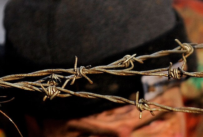 TELFORD, ENGLAND - JANUARY 31:  A competitor crawls under barbed wire as he takes part in the Tough Guy 2010 race on January 31, 2010 in Telford, England.  (Photo by Michael Regan/Getty Images)
