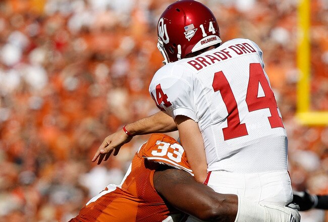 DALLAS - OCTOBER 17:  Quarterback Sam Bradford #14 of the Oklahoma Sooners is tackled by Lamarr Houston #33 of the Texas Longhorns at Cotton Bowl on October 17, 2009 in Dallas, Texas.  (Photo by Ronald Martinez/Getty Images)
