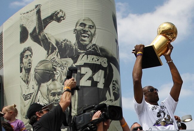 LOS ANGELES, CA - JUNE 21:  Los Angeles Lakers guard Kobe Bryant hoists the championship trophy as he rides past a mural featuring himself during the victory parade for the the NBA basketball champion team on June 21, 2010 in Los Angeles, California. The Lakers beat the Boston Celtics 87-79 in 7 games for the franchise's 16 NBA title.  (Photo by David McNew/Getty Images)