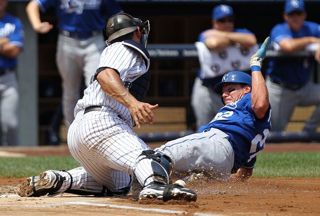 NEW YORK - JULY 24: Scott Podsednik #22 of the Kansas City Royals safely slide into home after Jorge Posada #20 of the New York Yankees dropped the ball at Yankee Stadium on July 24, 2010 in the Bronx borough of New York City.  (Photo by Nick Laham/Getty Images)