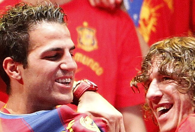 MADRID, SPAIN - JULY 12:  Pepe Reina (L) and Carles Puyol (R) of the Spanish national football team put a FC Barcelona shirt on Cesc Fabregas during the Spanish team's parade following their victory in the 2010 FIFA World Cup on July 12, 2010 in Madrid, Spain.  (Photo by Daniel Sastre/Getty Images)