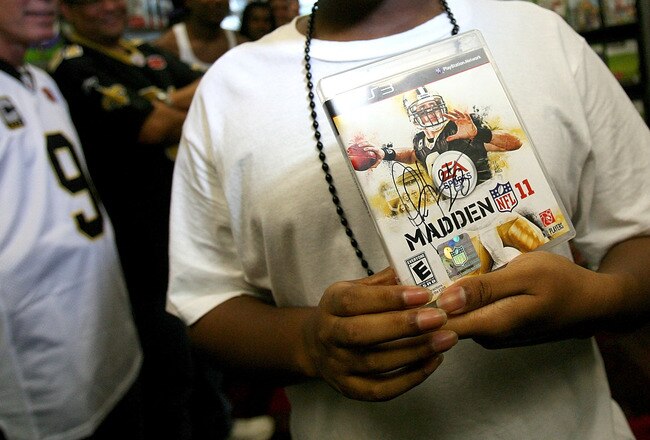 NEW ORLEANS - AUGUST 09: A very happy Ryan Jones, of New Orleans holds the first purchaced Madden NFL 11 video game signed by Marshall Faulk on August 9, 2010 in New Orleans, Louisiana. The game featuring New Orleans Saints quarterback Drew Brees goes on sale in stores at midnight on August 10.  (Photo by Sean Gardner/Getty Images)
