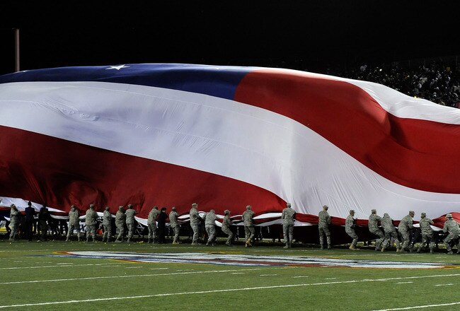 LAS VEGAS - DECEMBER 22:  Personnel from Nellis Air Force Base fight against high winds as they try to fold a giant American flag after pre-game ceremonies at the MAACO Las Vegas Bowl featuring the Brigham Young University Cougars and the Oregon State Beavers at Sam Boyd Stadium December 22, 2009 in Las Vegas, Nevada. The Cougars won 44-20.  (Photo by Ethan Miller/Getty Images)