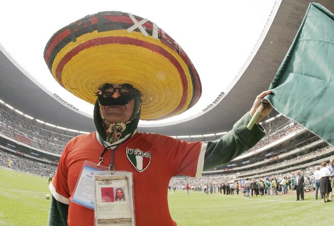 MEXICO CITY - MARCH 27:  Cuara Campo Isidro waves the Mexican flag before the start of the 2006 FIFA World Cup qualifying match between the USA and Mexico on March 27, 2005 at Estadio Azteca in Mexico City, Mexico.  Mexico won the game 2-1. (Photo by Brian Bahr/Getty Images)
