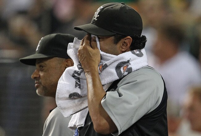 CHICAGO - AUGUST 10: Manager Ozzie Guillen #13 of the Chicago White Sox (R) wipes his face as bench coach Joey Cora watches a game against the Minnesota Twins at U.S. Cellular Field on August 10, 2010 in Chicago, Illinois. The Twins defeated the White Sox 12-6. (Photo by Jonathan Daniel/Getty Images)