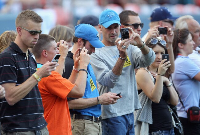 DENVER - AUGUST 21:  VIP fans on the sideline train their media capturing devices on the players during pregame warm ups as the Denver Broncos host the Detroit Lions during preseason NFL action at INVESCO Field at Mile High on August 21, 2010 in Denver, Colorado.  (Photo by Doug Pensinger/Getty Images)