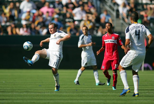 CARSON, CA - AUGUST 01:  Chris Birchall #11 of the Los Angeles Galaxy volleys the ball as Mike Banner #18 of the Chicago Fire looks on during their MLS match at The Home Depot Center on August 1, 2010 in Carson, California. The Fire defeated the Galaxy 3-2.  (Photo by Victor Decolongon/Getty Images)