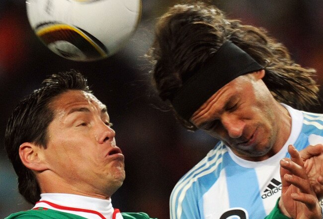 JOHANNESBURG, SOUTH AFRICA - JUNE 27:  Guillermo Franco of Mexico and Martin Demichelis of Argentina jump for the ball during the 2010 FIFA World Cup South Africa Round of Sixteen match between Argentina and Mexico at Soccer City Stadium on June 27, 2010 in Johannesburg, South Africa.  (Photo by Stanley Chou/Getty Images)